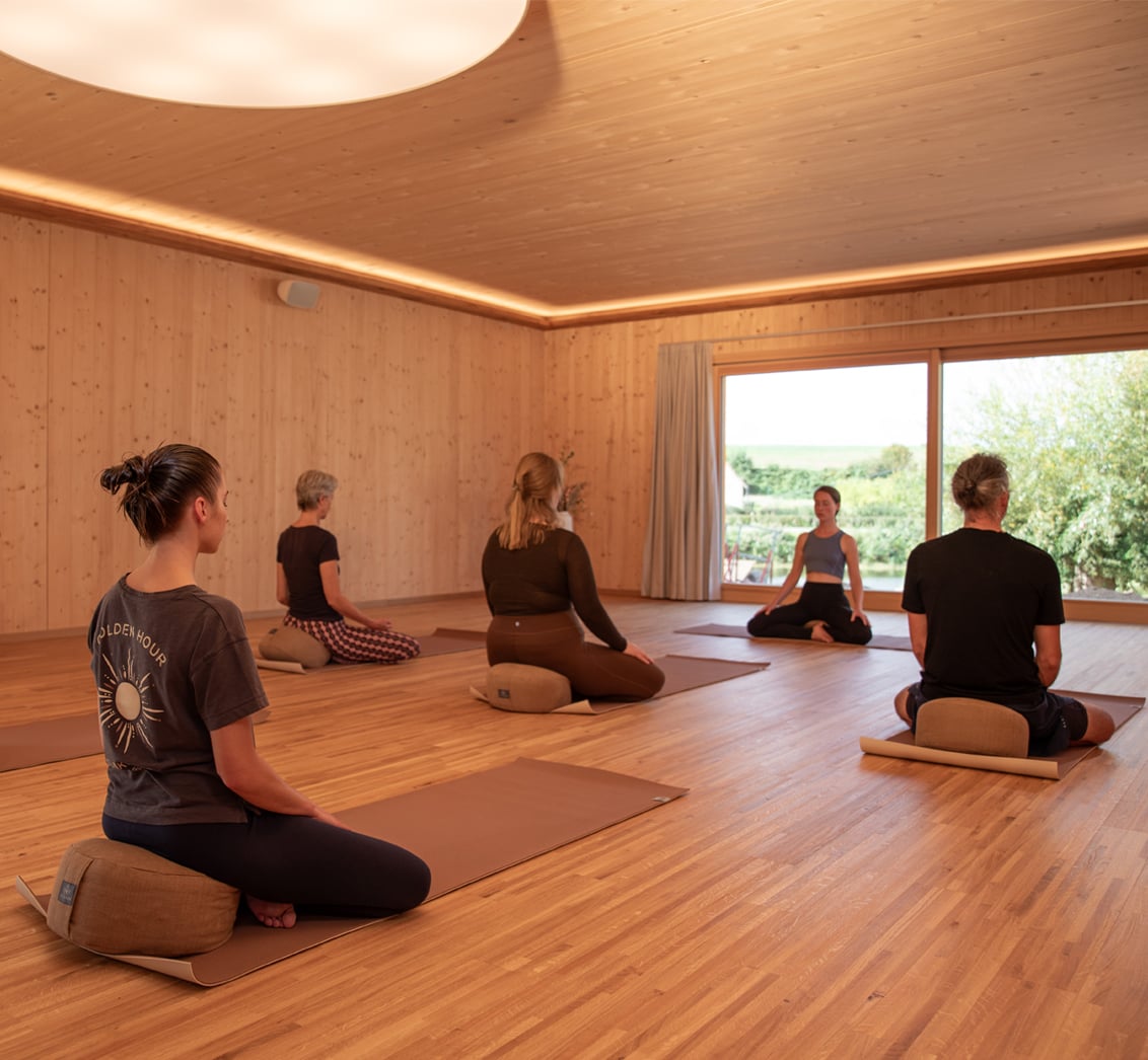 Yogaklasse in Holzstudio mit Teilnehmern auf Matten